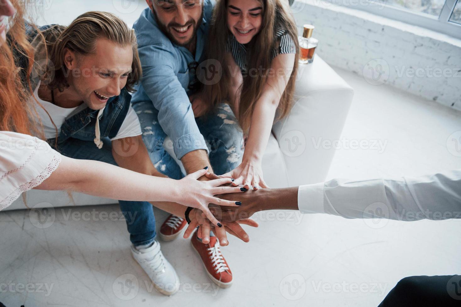 equipe engraçada e rindo de amigos unidos de mãos dadas foto