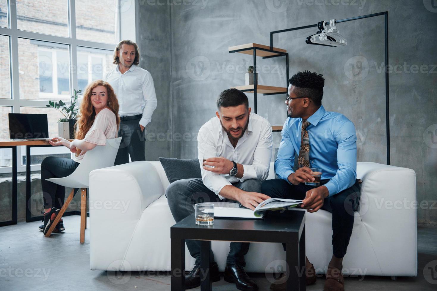 interação completa. grupo de funcionários multirraciais em roupas formais conversando sobre tarefas e planos foto