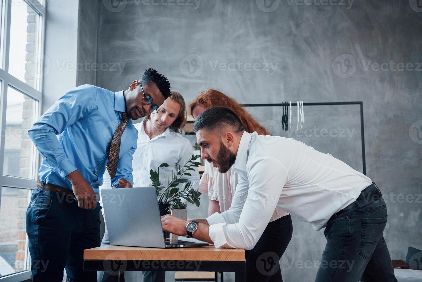 mesa cercada. quatro jovem empresário trabalhando no plano usa notebook foto