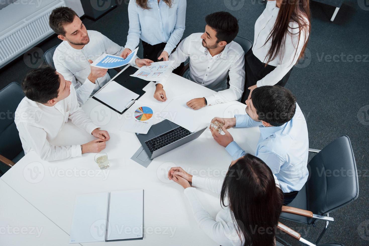 concentrado no trabalho. vista superior de funcionários de escritório em roupas clássicas sentados perto da mesa usando laptop e documentos foto