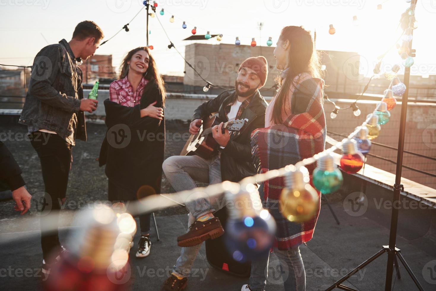 tocando música e cantando. festa na cobertura com álcool e violão em um dia ensolarado de outono foto