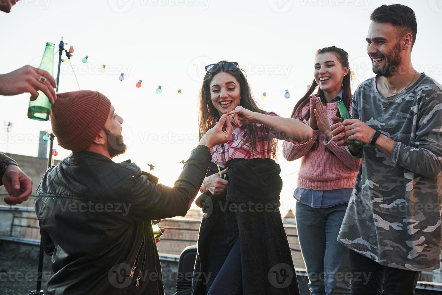 garota dá seu dedo mindinho. declaração de amor no telhado com a companhia de amigos foto