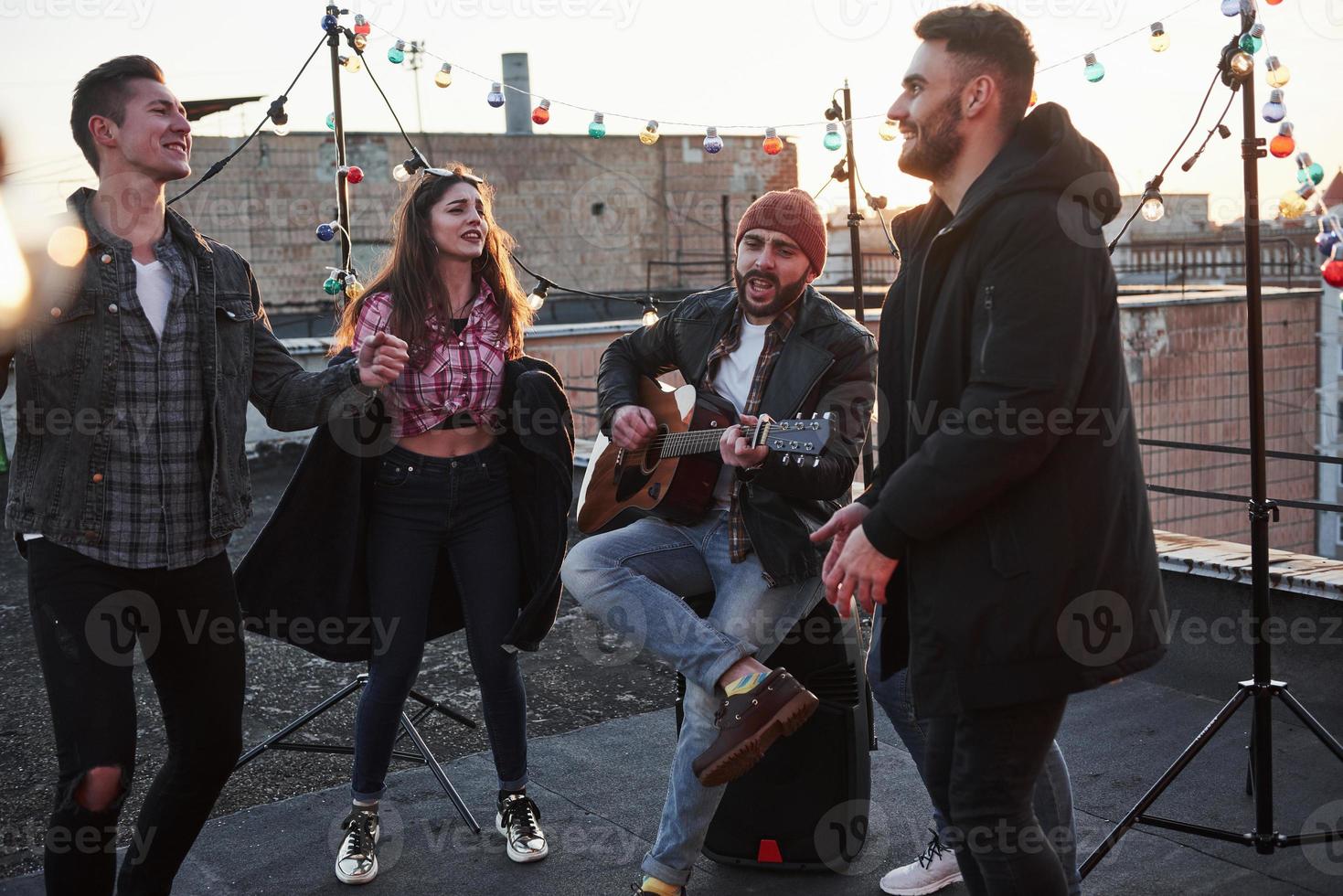 parece uma música emocional. violão tocando e cantando no telhado ao pôr do sol foto