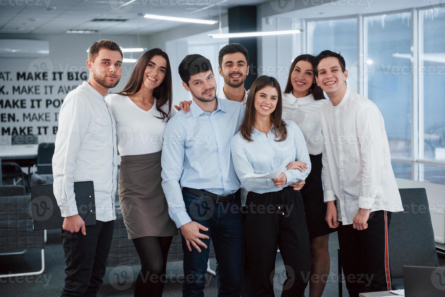 feliz em trabalhar juntos. retrato da equipe jovem em roupas clássicas no escritório moderno bem iluminado foto