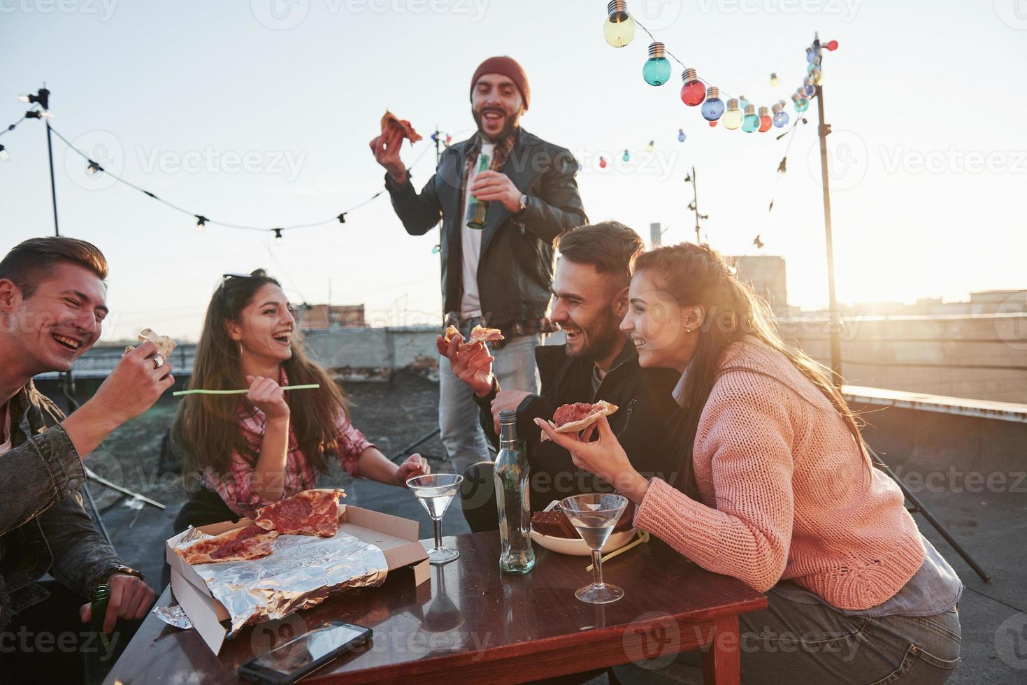 piadas engraçadas. comendo pizza na festa do telhado. bons amigos tenham fim de semana com comida deliciosa e álcool foto