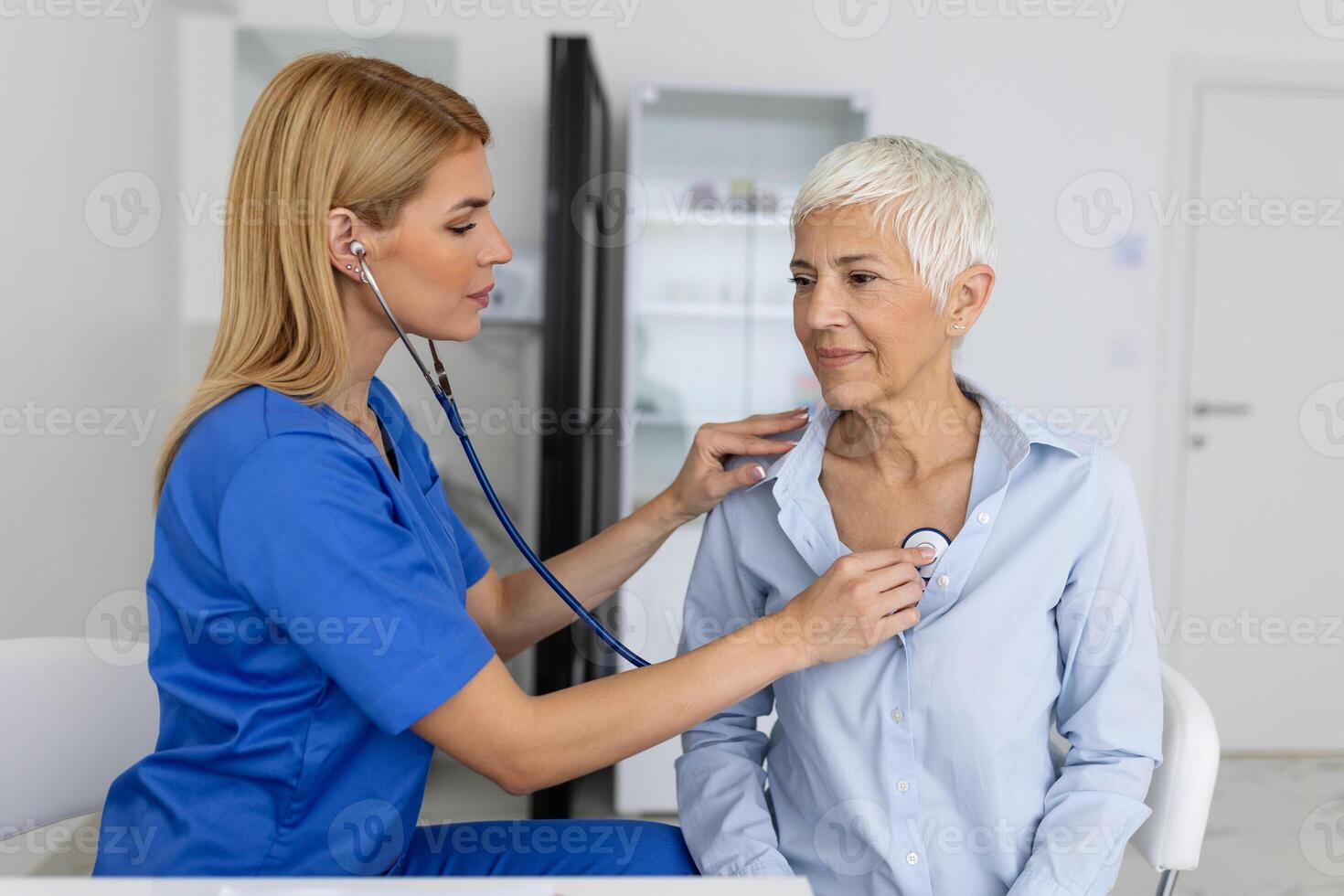 jovem fêmea médico ouço para Senior paciente coração peito com estetoscópio às clínica reunião. mulher gp checar examinar mulher cliente com estetoscópio. cuidados de saúde conceito. foto