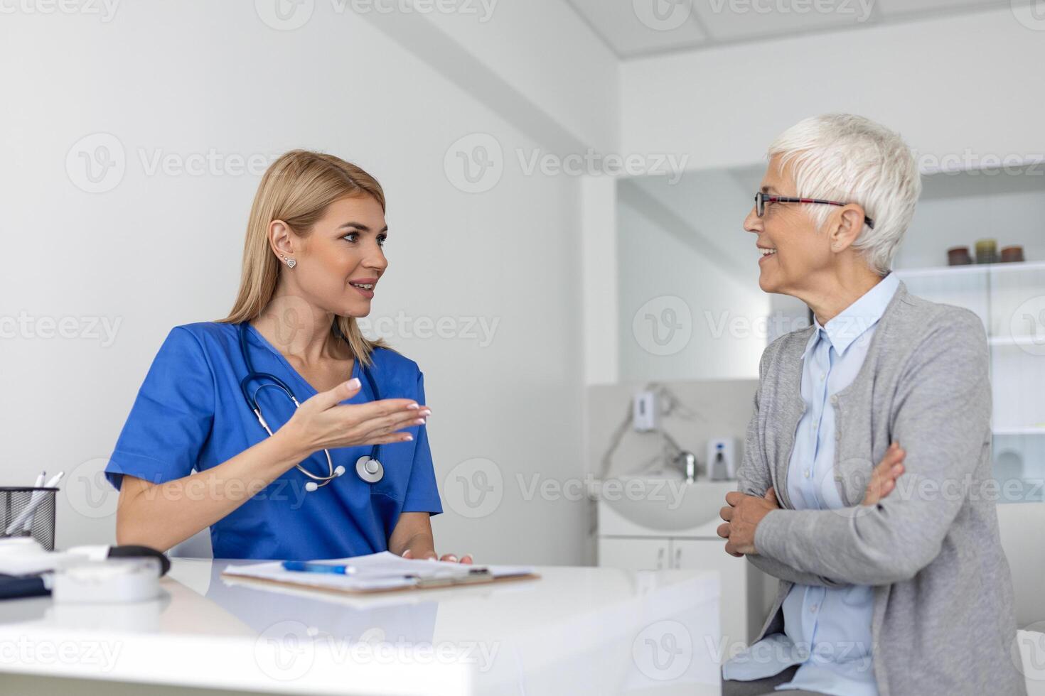 jovem mulher médico ou gp dentro branco médico uniforme consultar Senior fêmea paciente dentro privado hospital. fêmea terapeuta falar conversa com mulher cliente em consulta dentro clínica. foto