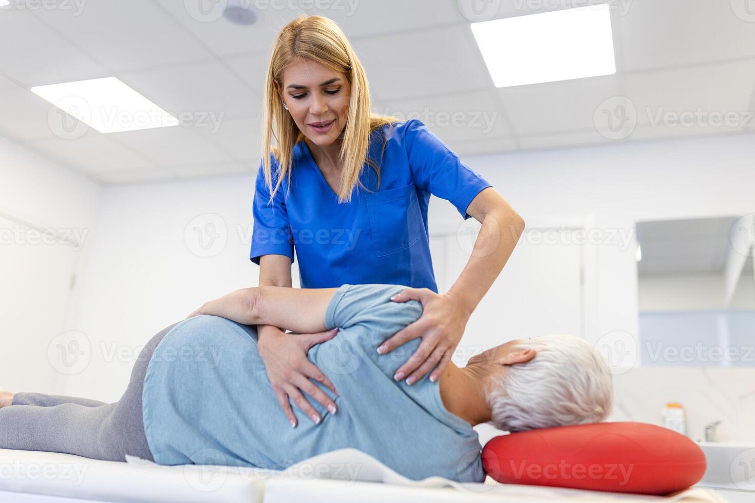 médico ou fisioterapeuta ajuda para curar uma Senior mulher voltar. e dar adendo dentro a reabilitação Centro. conceito do fisica reabilitação. foto
