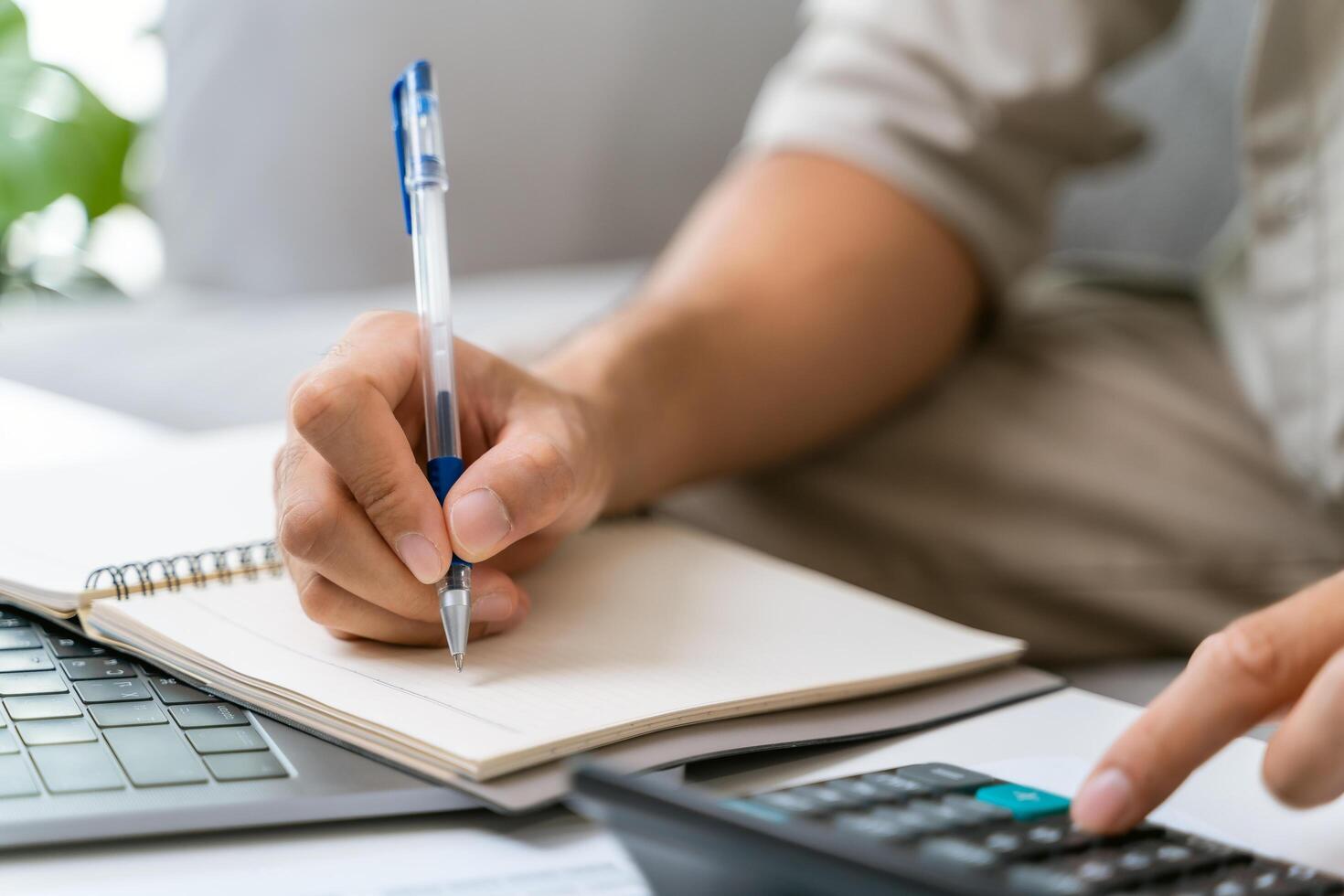 uma homem é escrevendo dentro uma caderno com uma caneta e uma calculadora foto