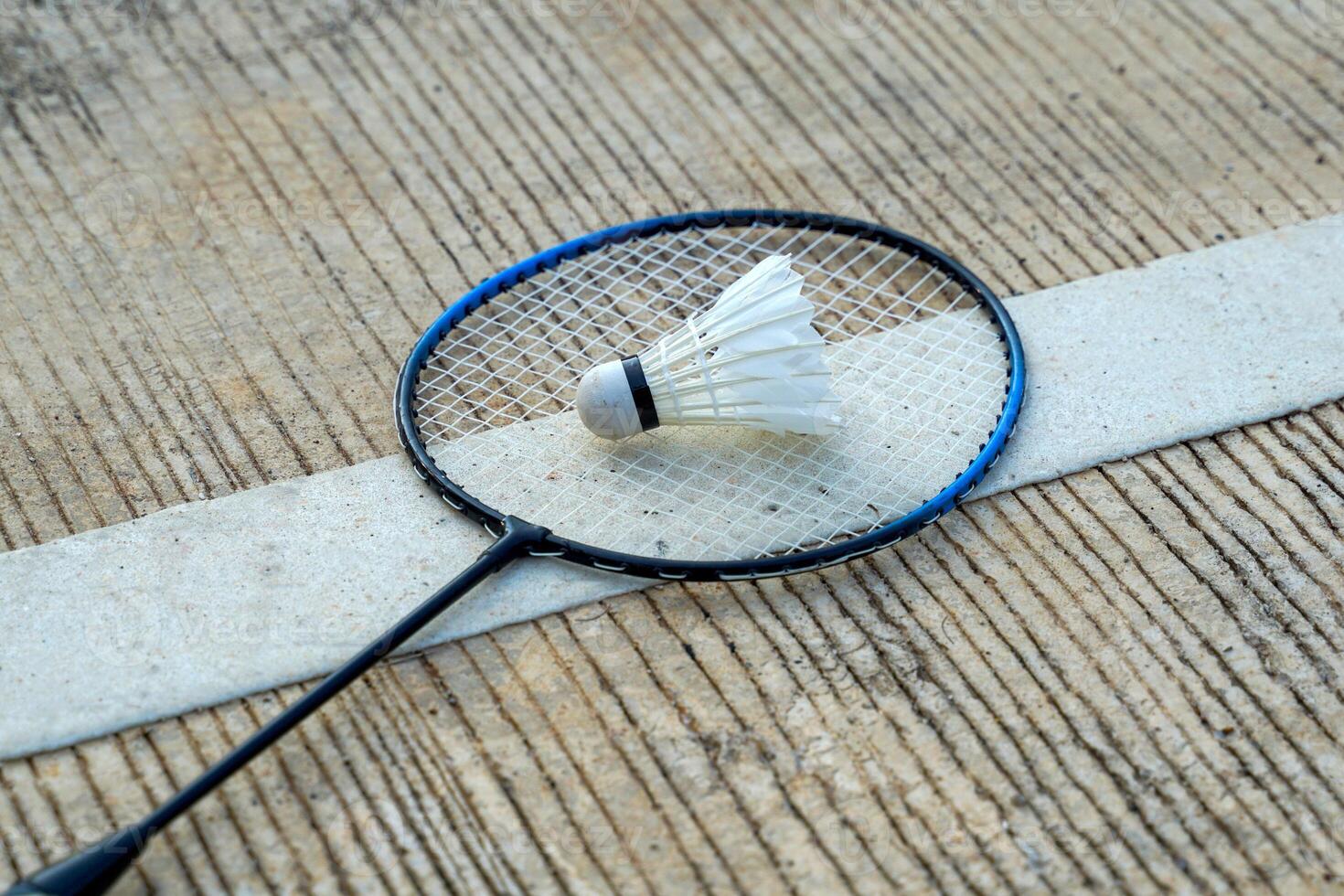badminton raquete e branco peteca colocada em cimento fundo. suave e seletivo foco. foto