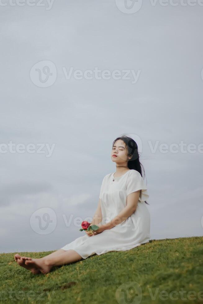 retrato do uma bonita jovem mulher vestido dentro branco vestir segurando rosa flores foto