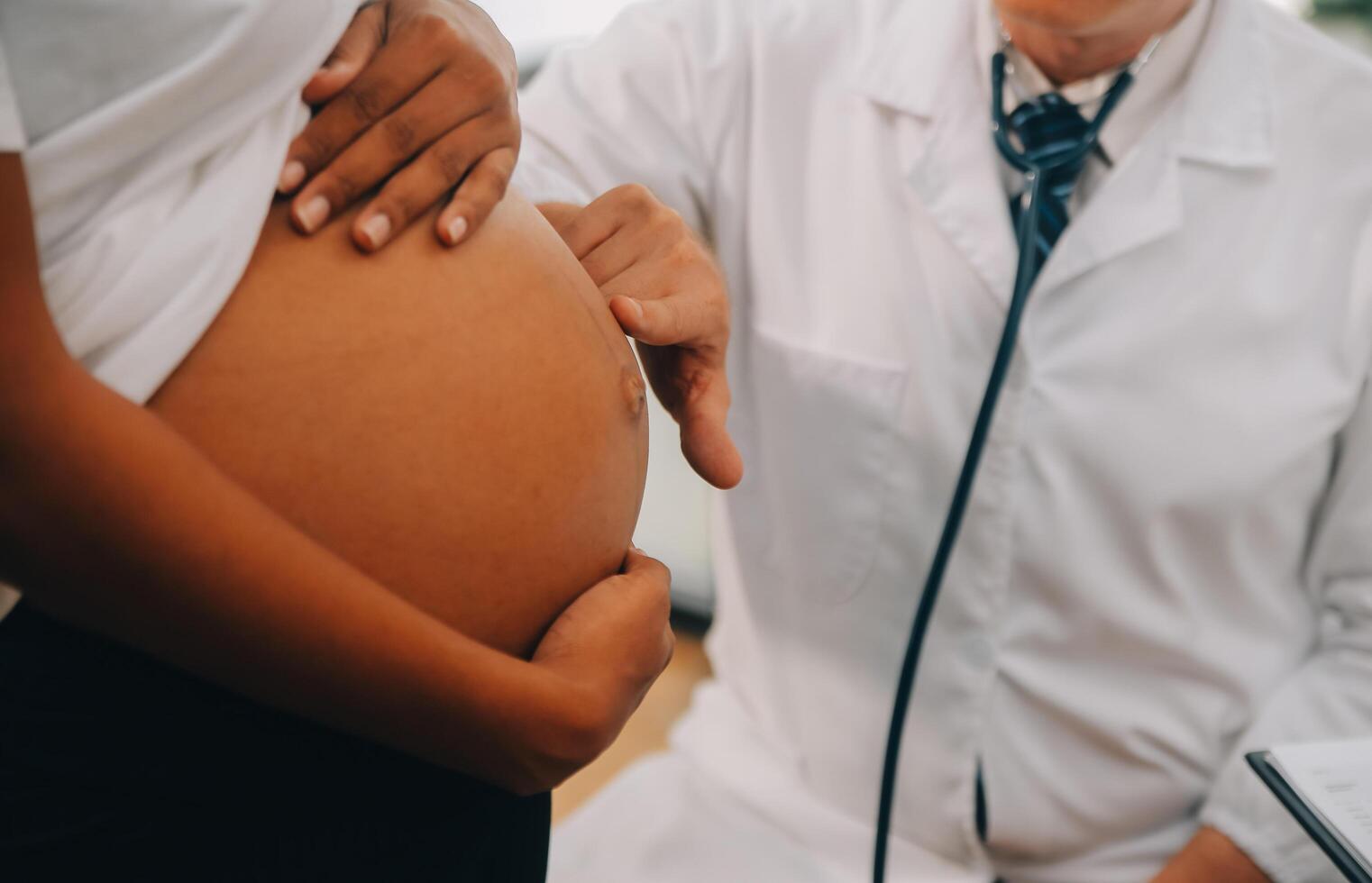 fêmea médico é verificação grávida mulher com estetoscópio. conceito carinhoso para grávida mulher foto