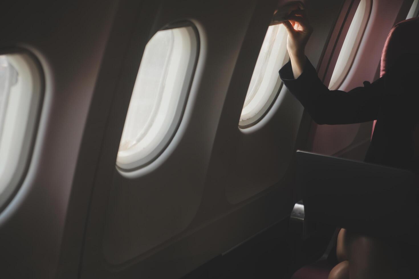 Loiras fêmea turista verificação entrada notificação em Smartphone sentado em assento do avião com netbook.jovem empresária compartilhar meios de comunicação a partir de Telefone em computador portátil computador durante avião voar foto