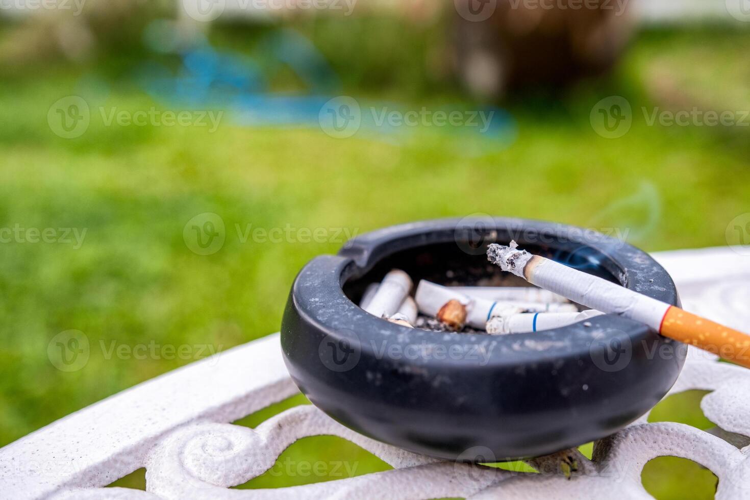 cigarro queimando com fumaça em cerâmico cinzeiro foto