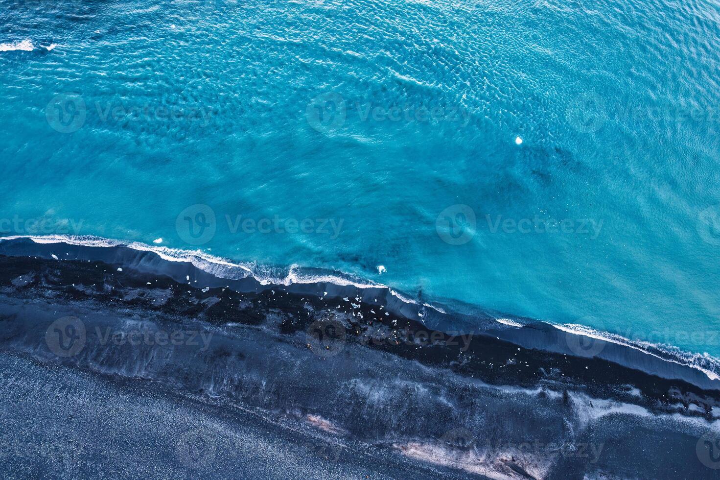 dramático azul mar com ondulação onda erosão texturizado em Preto areia de praia foto