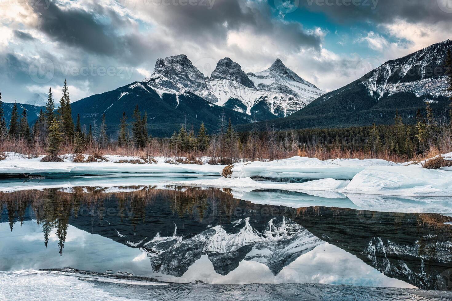 Visão do três irmãs montanhas com neve coberto em congeladas arco rio reflexão dentro a manhã em inverno às Canadá foto