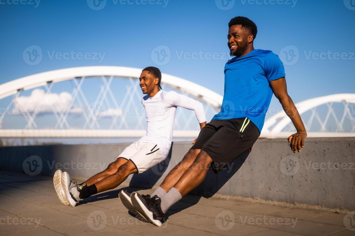 dois amigos estão exercício dentro a cidade. elas estão fazendo marcha ré flexões. foto