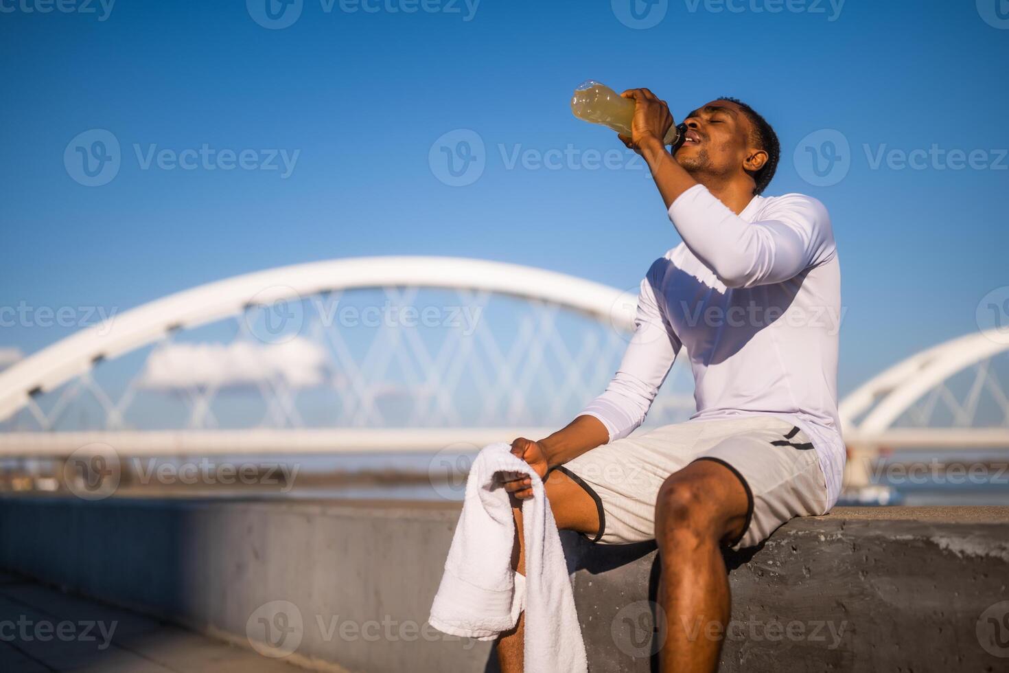 retrato do jovem afro-americano homem quem é bebendo refresco beber e relaxante depois de corrida. foto