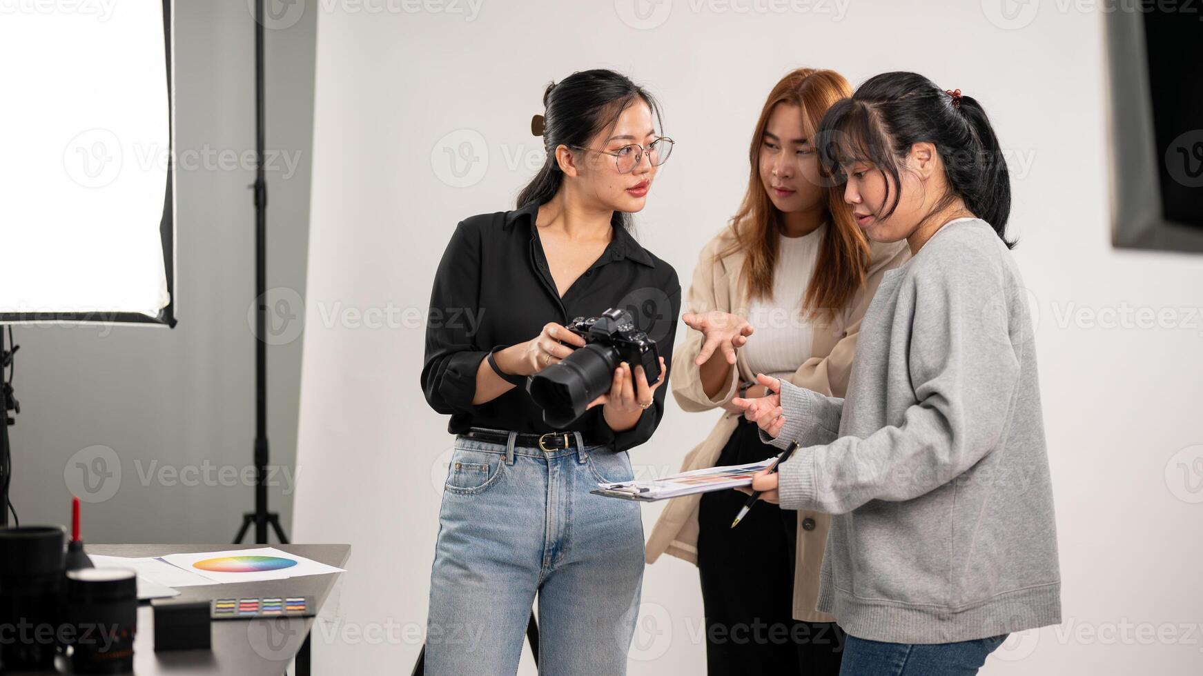 uma fêmea fotógrafo é falando e mostrando imagens em a Câmera para dela equipe, trabalhando dentro a estúdio foto