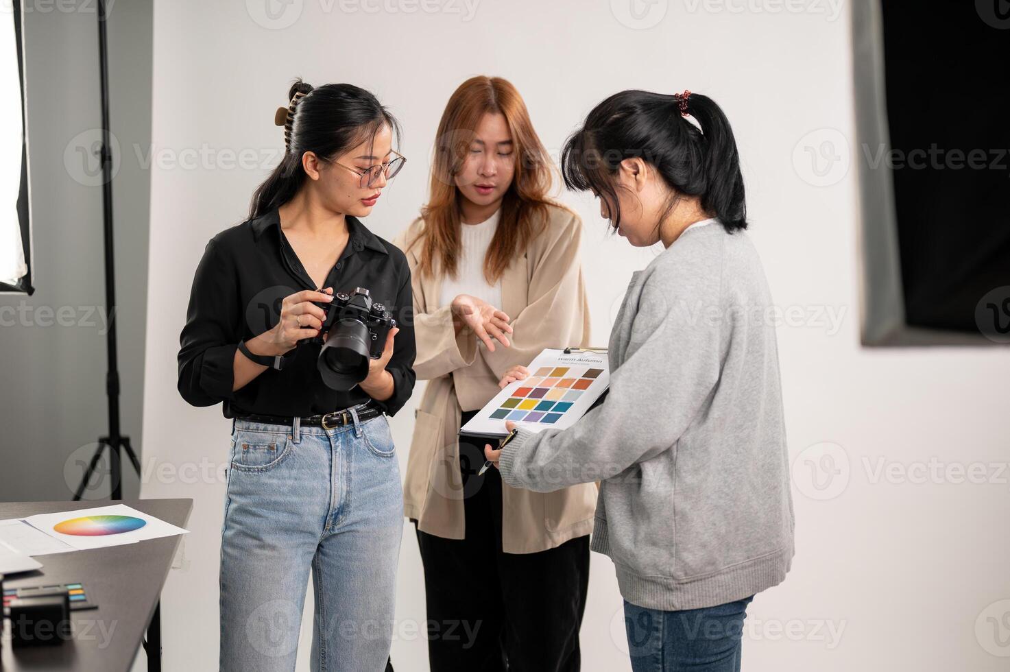 uma profissional ásia fêmea fotógrafo falando com assistentes, preparando antes uma tiroteio. foto