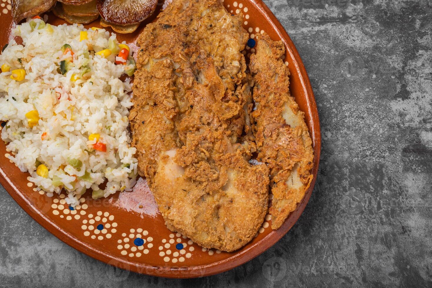 panado frito peixe e arroz dentro uma argila prato em uma de madeira mesa. foto