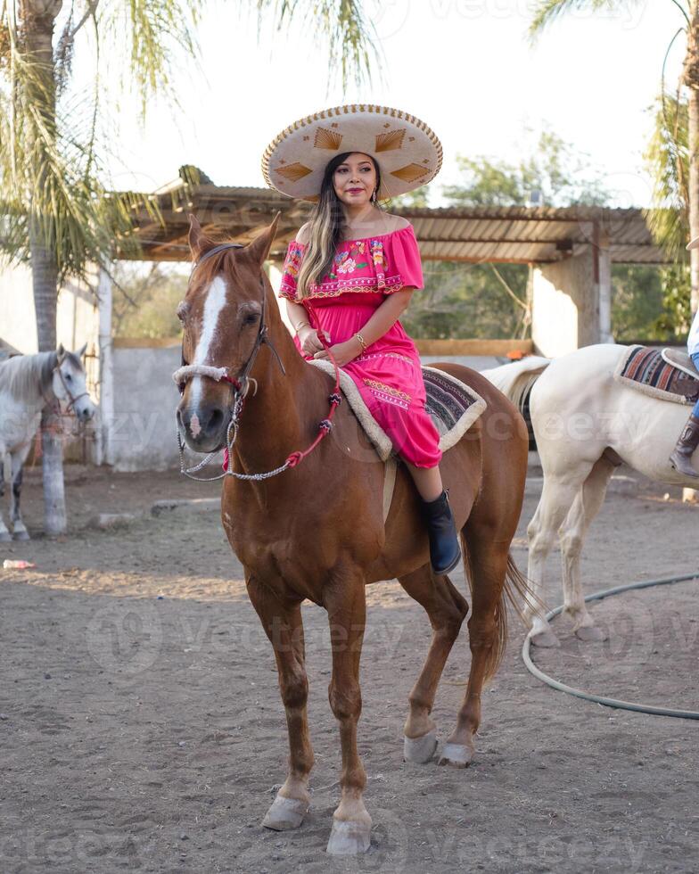 mexicano mulher vestindo tradicional vestir e charro chapéu em a cavalo. cinco de maionese celebração. foto