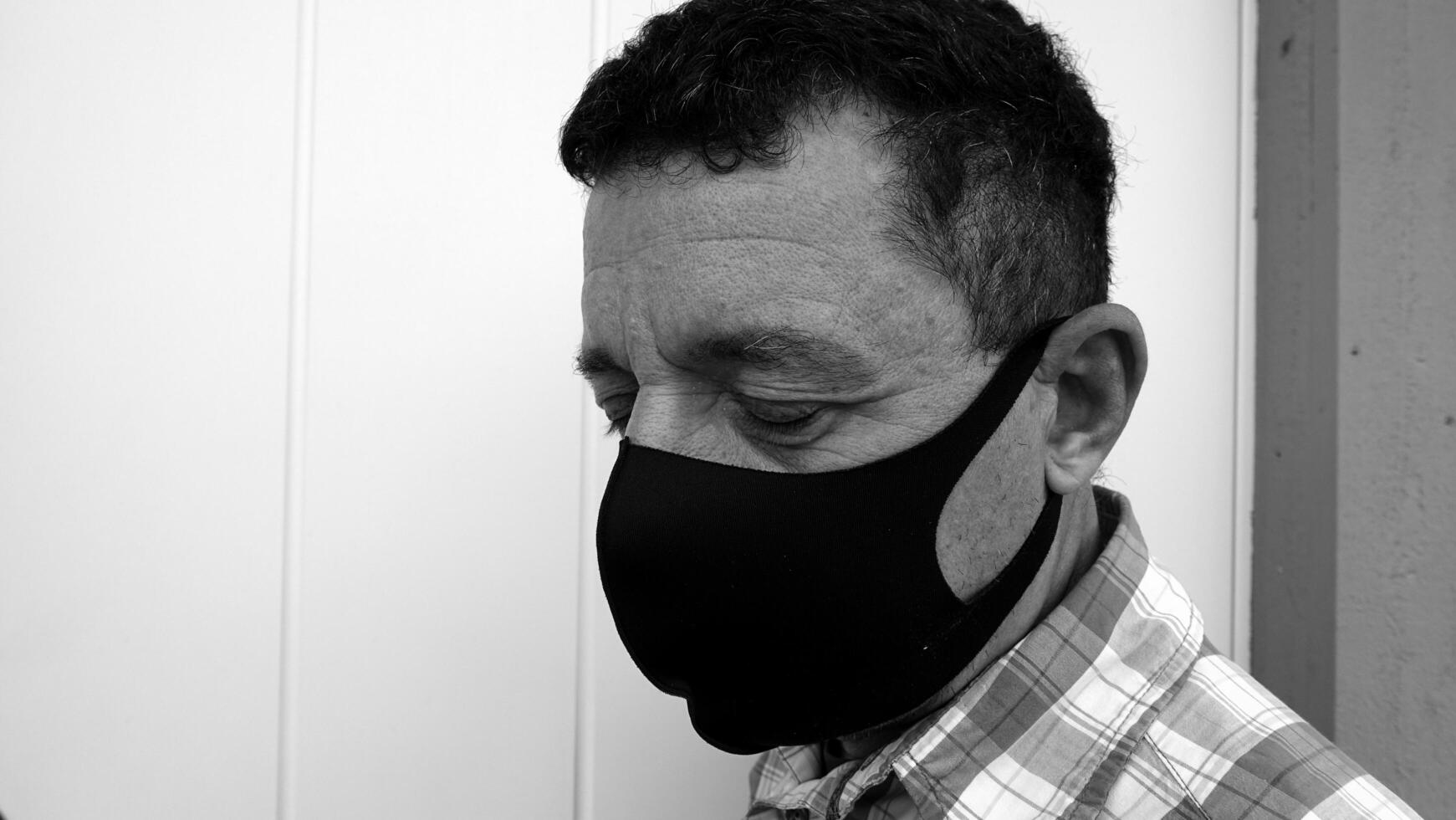 imagem este retrata a face do uma homem com uma Preto protetora anti-contágio mascarar foto