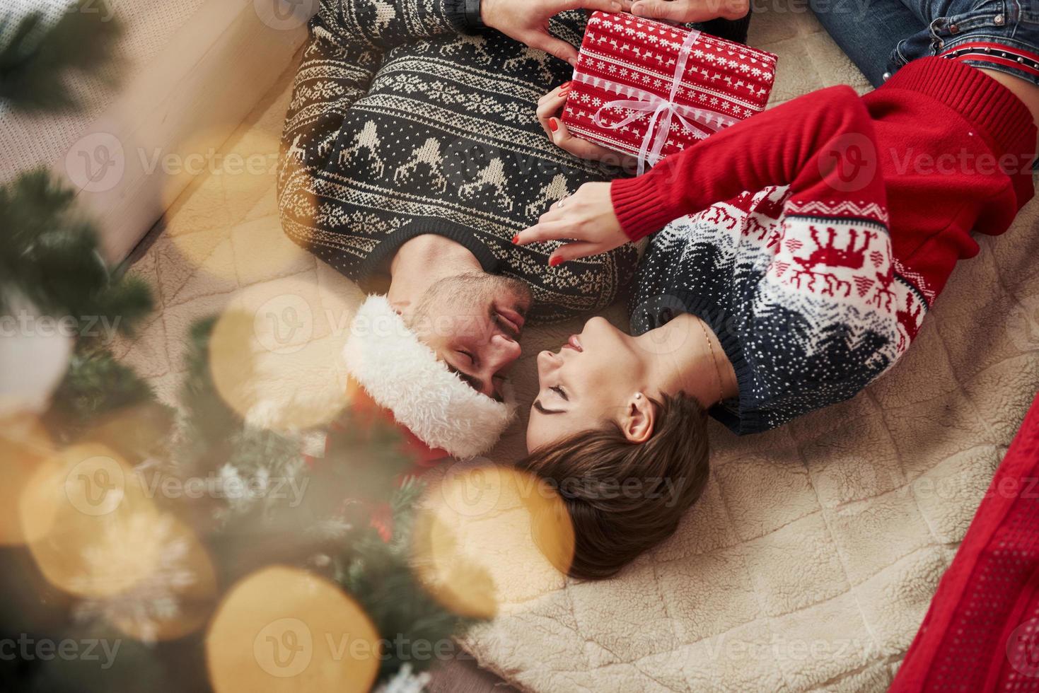 foto invertida de um jovem casal comemorando o ano novo e segurando uma caixa de presente