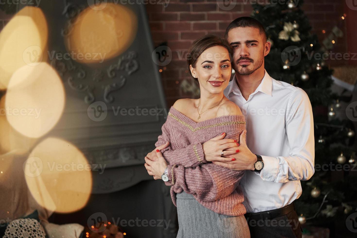 amantes doces e elegantes. casal legal comemorando ano novo na frente da árvore de natal foto