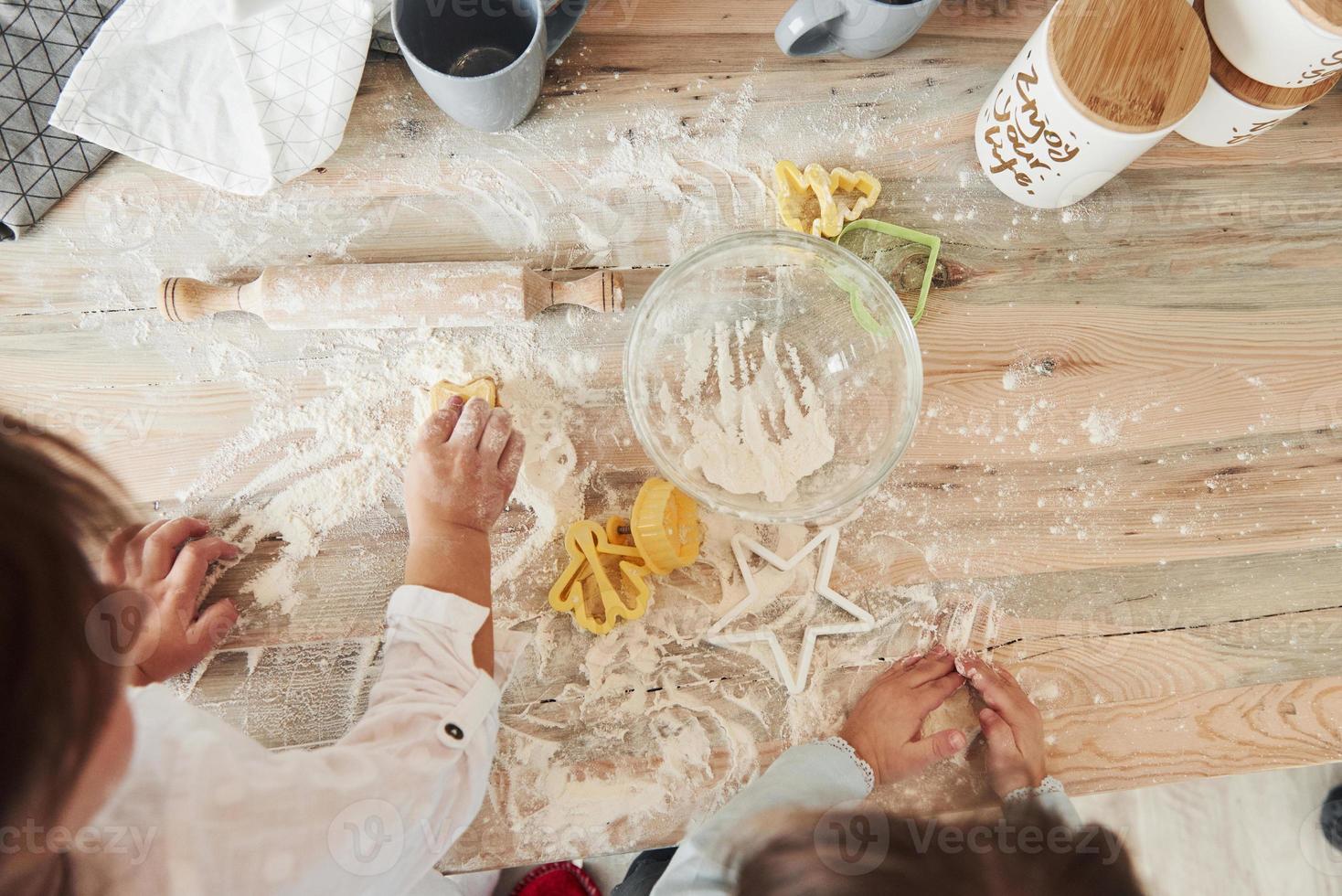processo criativo. vista superior de crianças aprendendo a preparar comida com farinha com instrumentos especiais foto