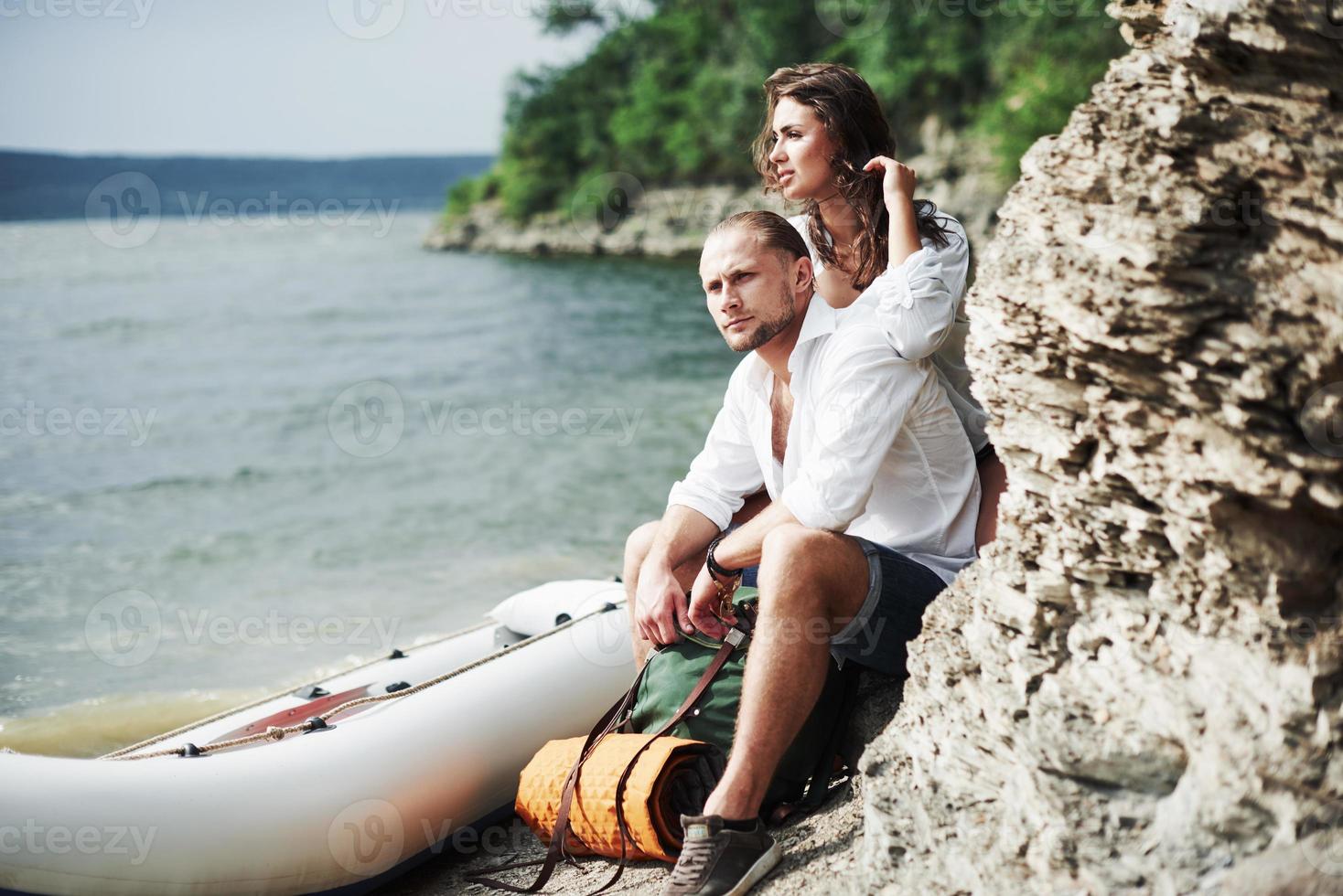 olhar pensativo. turistas satisfeitos com a viagem que fazem no fundo de árvores perto de um barco foto