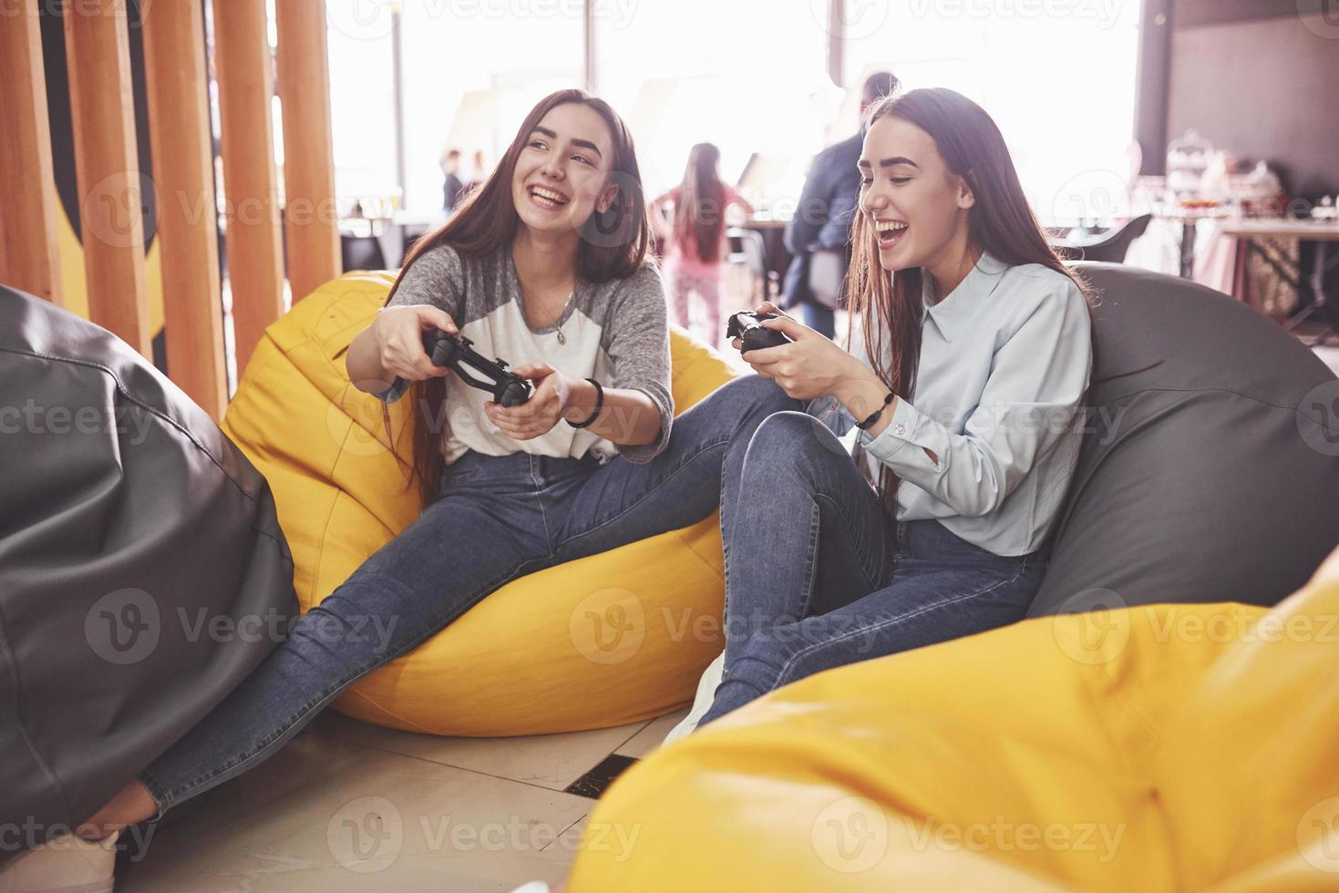 irmãs gêmeas jogam no console. meninas seguram joysticks nas mãos e se divertem foto