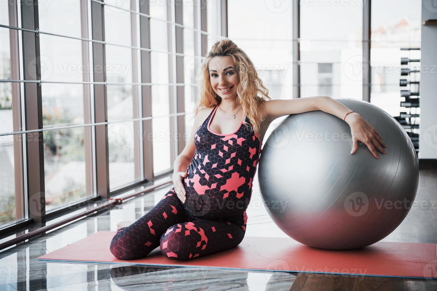 jovem grávida sentada e segurando uma bala para fazer exercícios foto