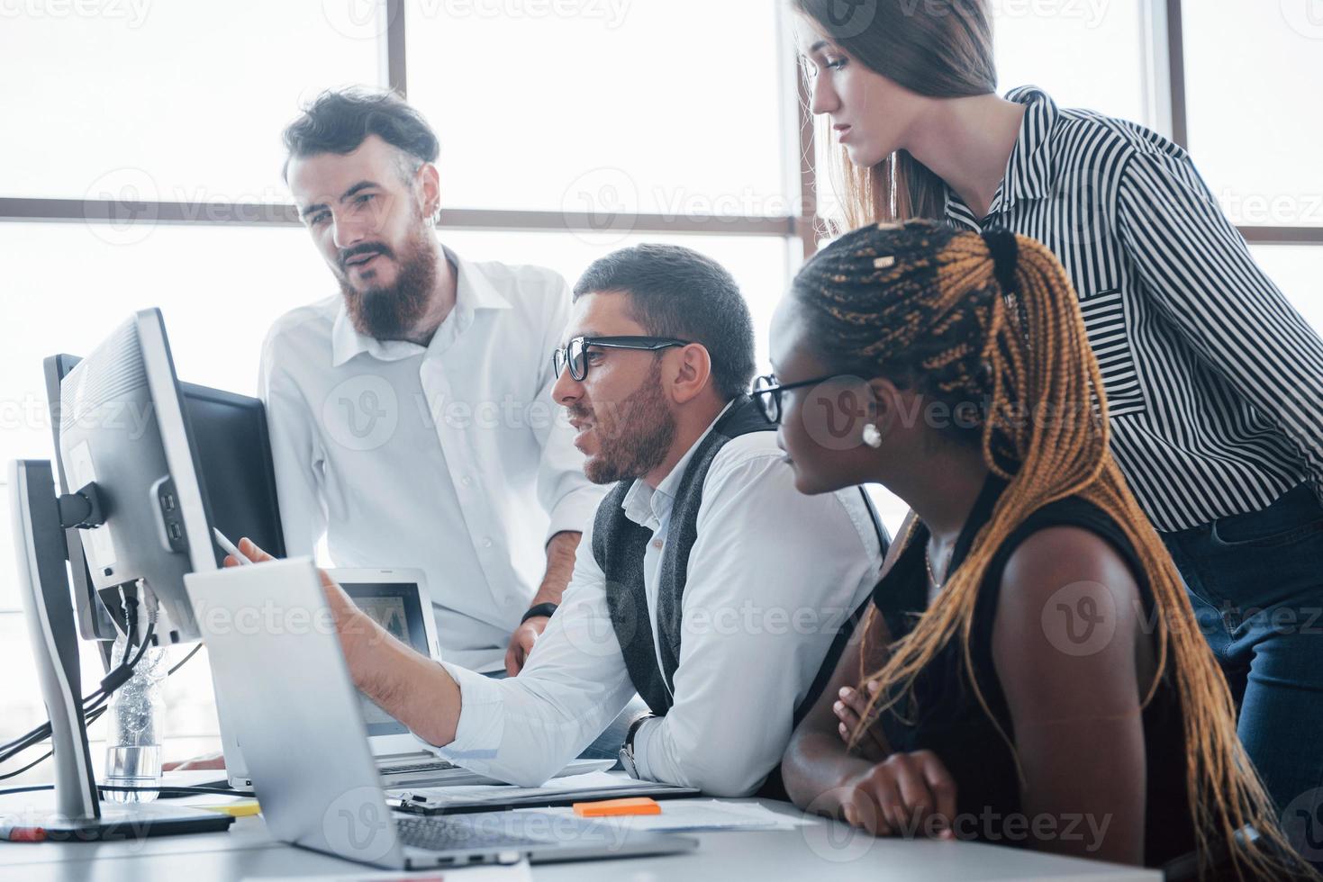 jovens funcionários sentados no escritório à mesa e usando um laptop, um conceito de reunião de brainstorming de trabalho em equipe. foto