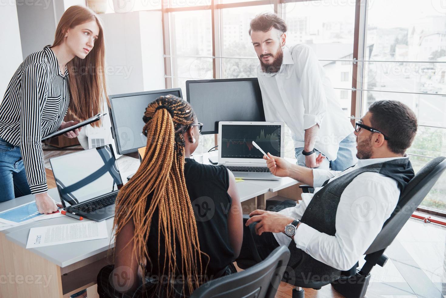 jovens funcionários sentados no escritório à mesa e usando um laptop, um conceito de reunião de brainstorming de trabalho em equipe. foto