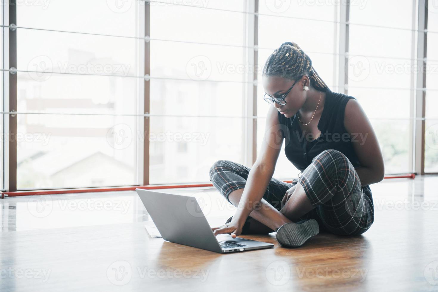 uma jovem afro-americana está feliz com um computador portátil. foto