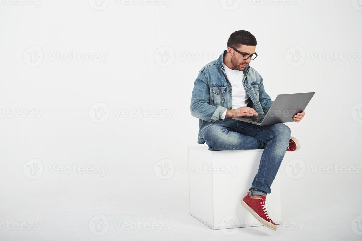 jovem bonito com laptop e verificar seu calendário em fundo branco foto