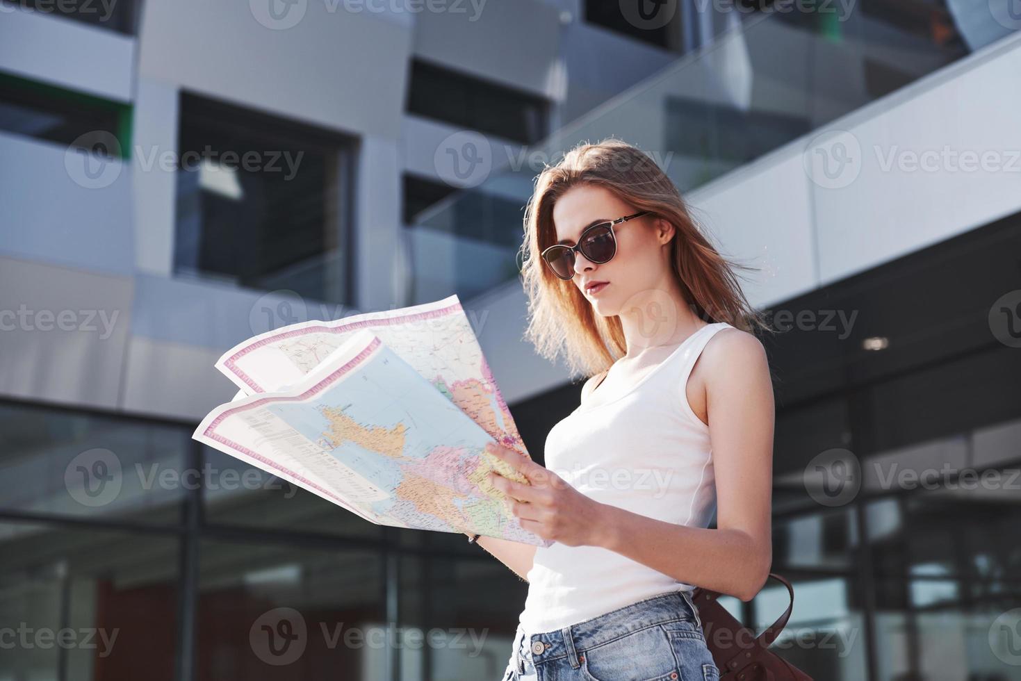 turista feminina com mapa visitando uma nova cidade e procurando um caminho para o hotel foto