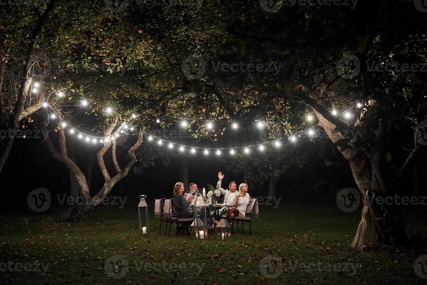 chame o garçom. hora da noite. amigos jantam em um lindo lugar ao ar livre foto