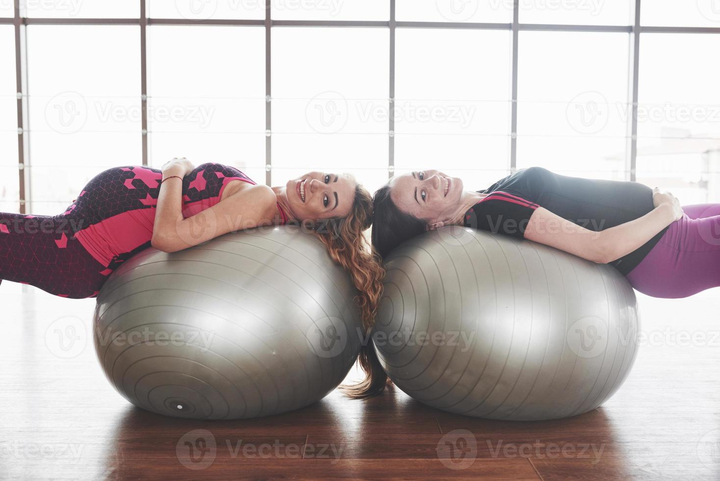 meninas na academia deitadas em duas bolas de estabilidade durante a gravidez e sorrindo foto