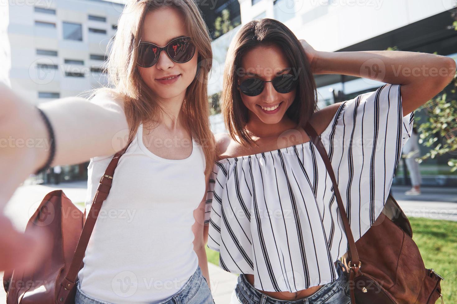 duas linda feliz jovem estudante com mochila perto do campus da universidade e fazer selfie foto. conceito de educação e lazer foto