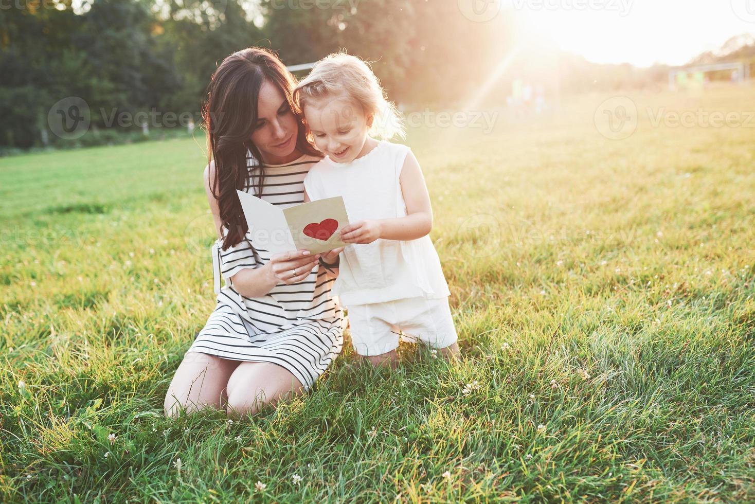 mãe e filha sentadas e lendo o livrinho com o coração na capa foto