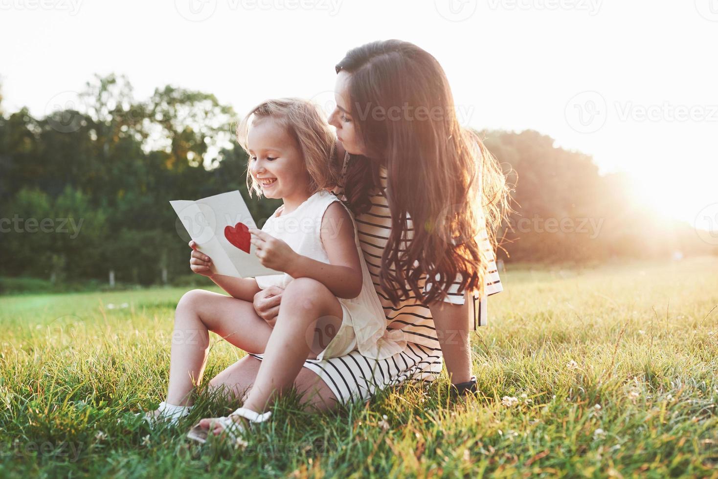 aprender é divertido. mãe e filha sentadas e lendo o livrinho com o coração na capa foto