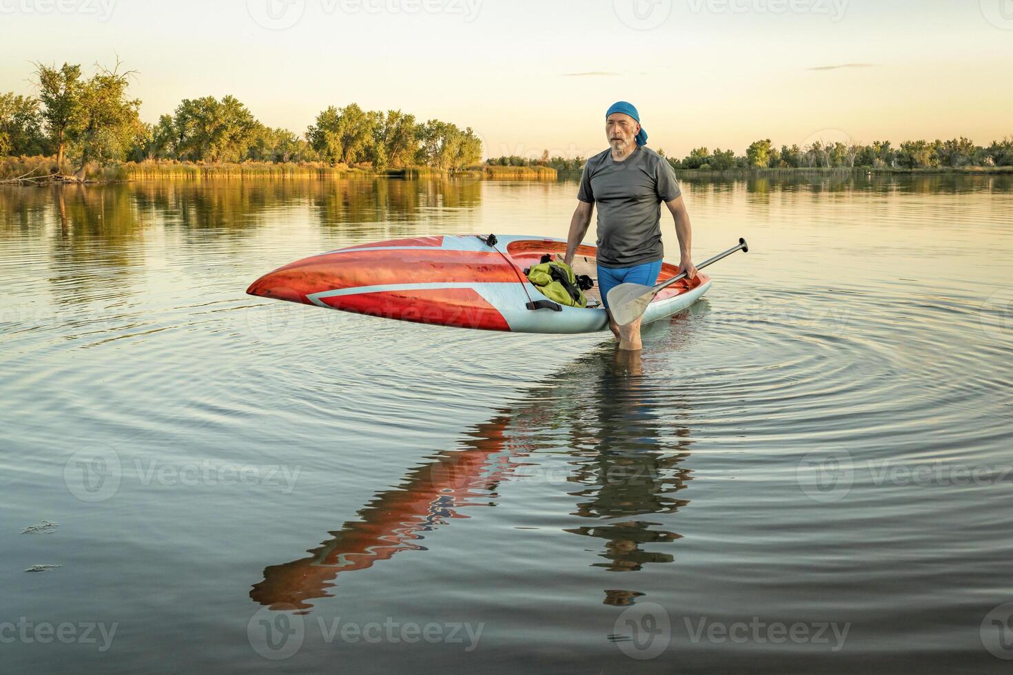 Senior remador com uma corrida ficar de pé acima paddleboard foto