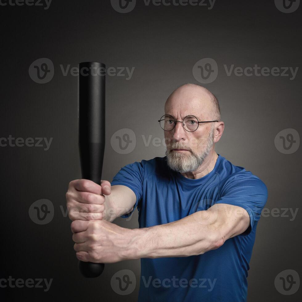 Senior homem é exercício com uma aço clube foto