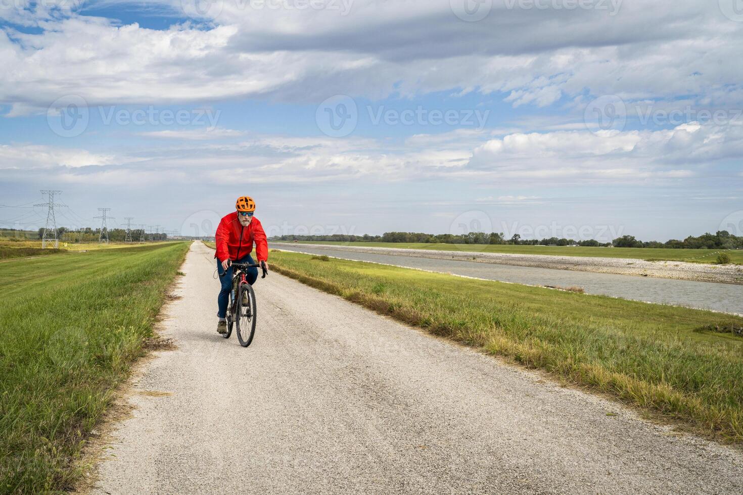 Senior Atlético homem é equitação uma cascalho excursão bicicleta - ciclismo em uma dique trilha ao longo cadeia do pedras canal perto granito cidade dentro Illinois foto