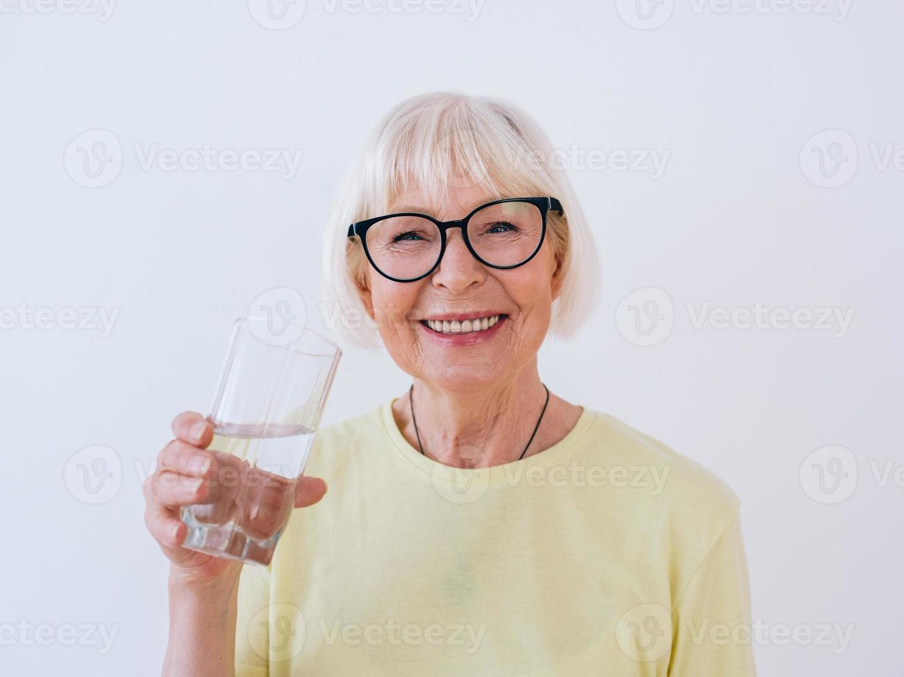 sênior mulher segurando um copo de água e água potável. estilo de vida saudável, esporte, conceito anti-idade foto