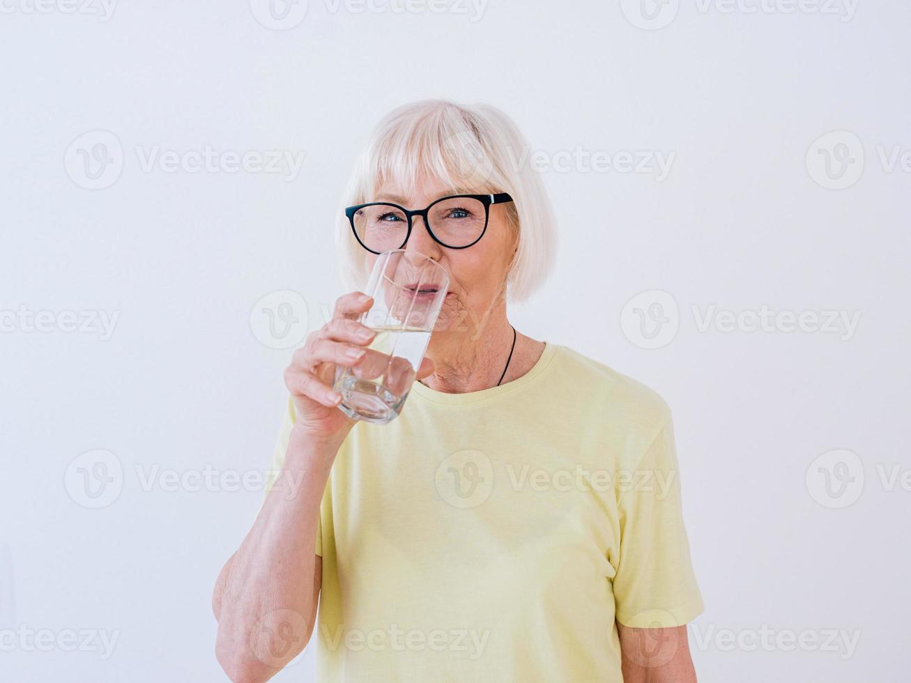 sênior mulher segurando um copo de água e água potável. estilo de vida saudável, esporte, conceito anti-idade foto