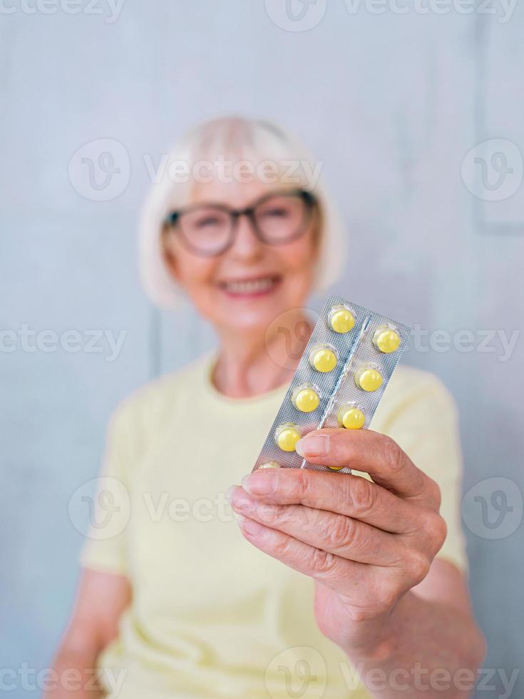 mulher sorridente sênior com comprimidos na mão. cuidados de saúde, médicos, tratamento, conceito de idade foto