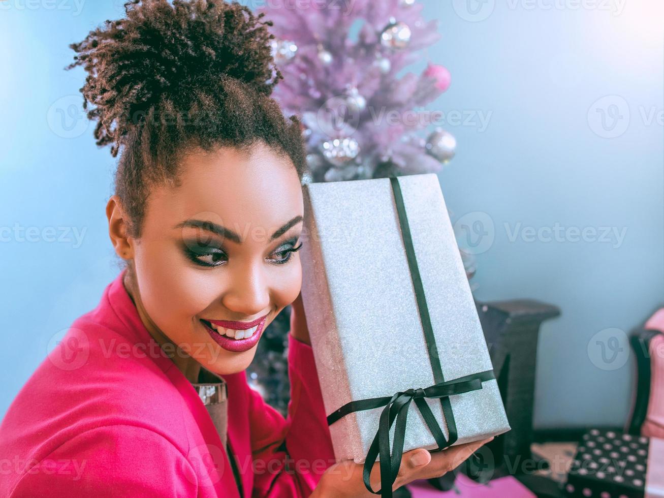 bela atraente alegre sorridente jovem mista rase segurando o presente do dia nas mãos foto